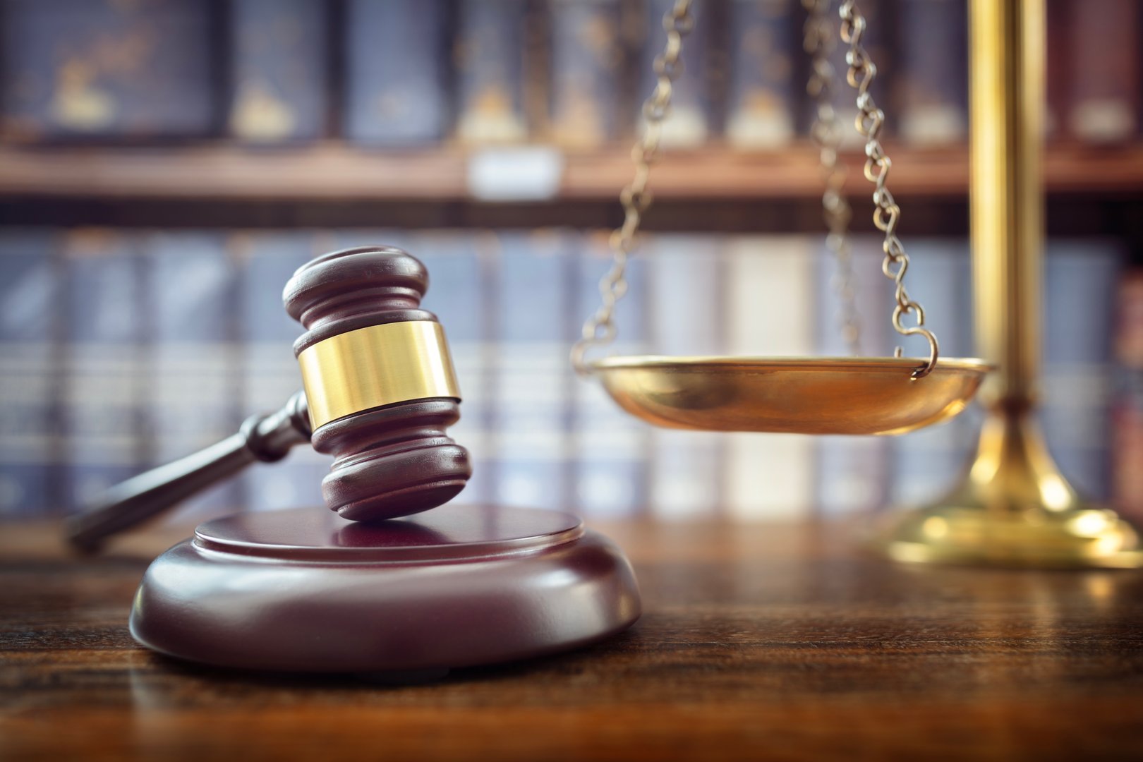 Judge gavel, scales of justice and law books in court background