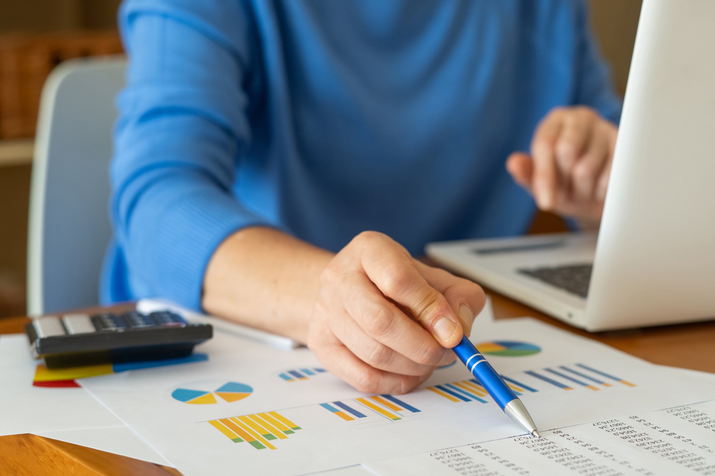 Businesswoman is analyzing financial charts and data with a pen and laptop, developing investment strategies and making informed decisions