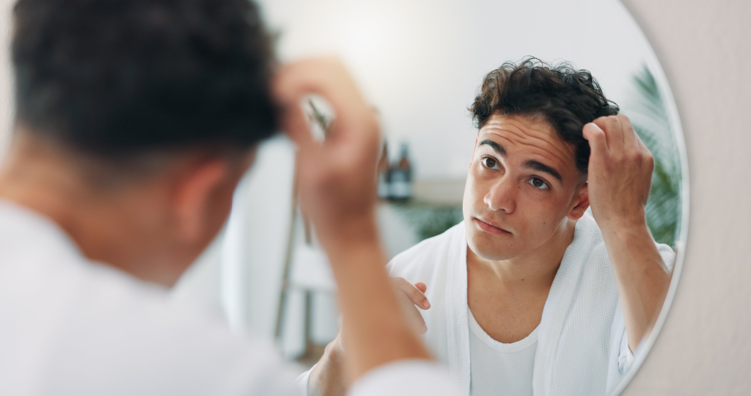 House, mirror and man with hair care, bathroom and grooming with routine, volume and texture. Person, apartment and guy with concern, shampoo and worry for balding, dry scalp and dandruff with growth