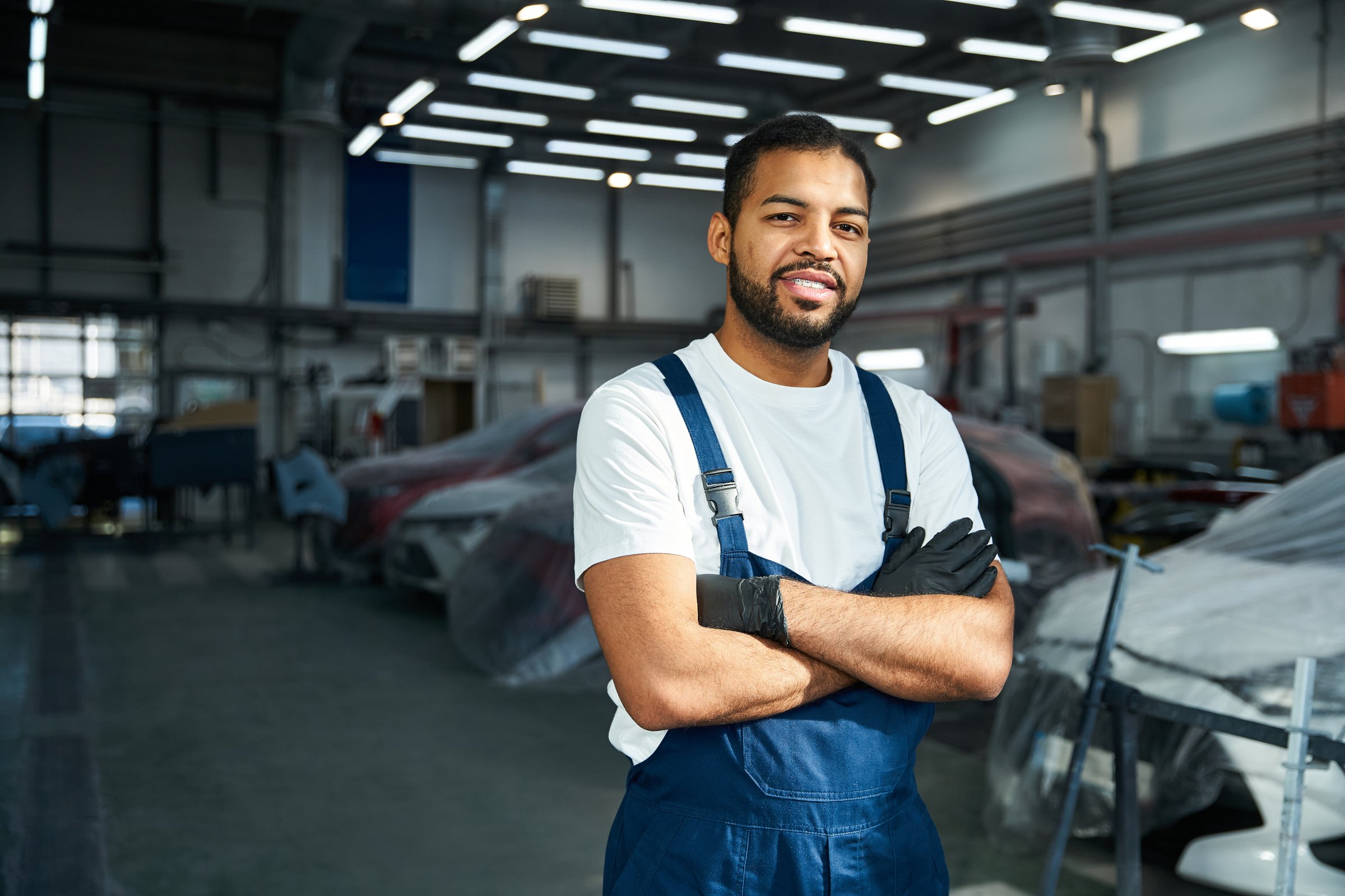 Young mechanic engages in car maintenance duties at a busy repair center.