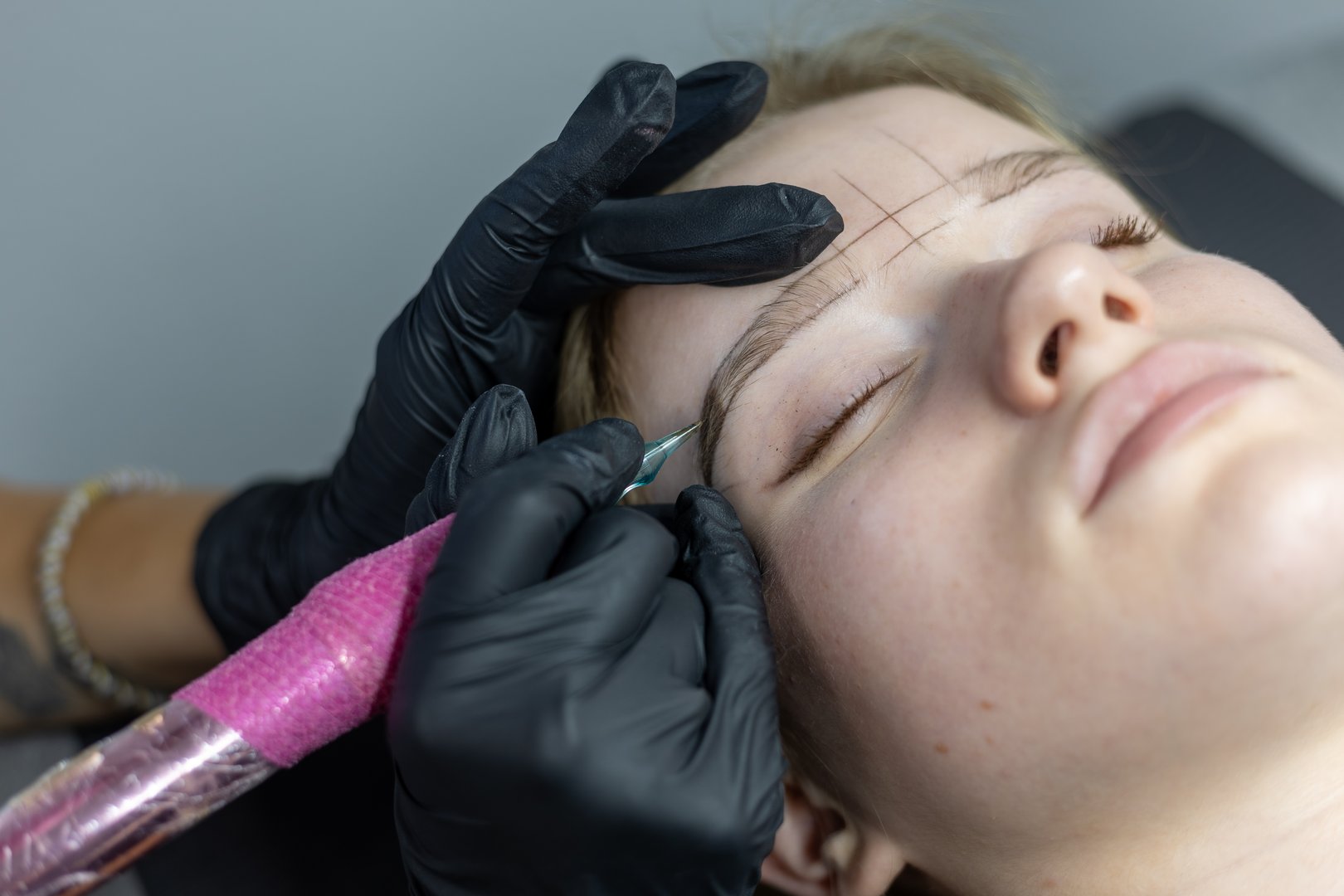 A skilled artist carefully applies microblading technique to enhance the eyebrows of a client in a modern beauty studio setting.