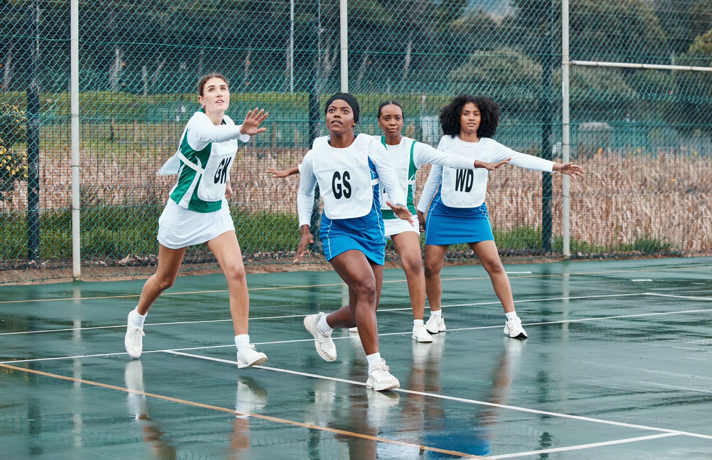Sports, netball team and portrait of women training in competition, game or match. Fitness, group and girls workout on court, exercise and practice performance on wet ground outdoor for healthy body