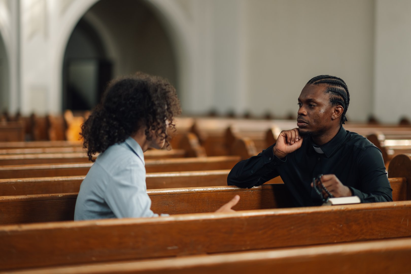Priest listens to a man in church, offering support and guidance with empathy. The scene radiates comfort and solace, capturing a moment of faith and compassion