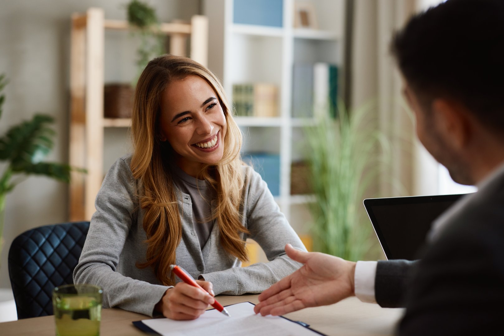 Businesswoman smiling and signing contract after successful negotiation with businessman