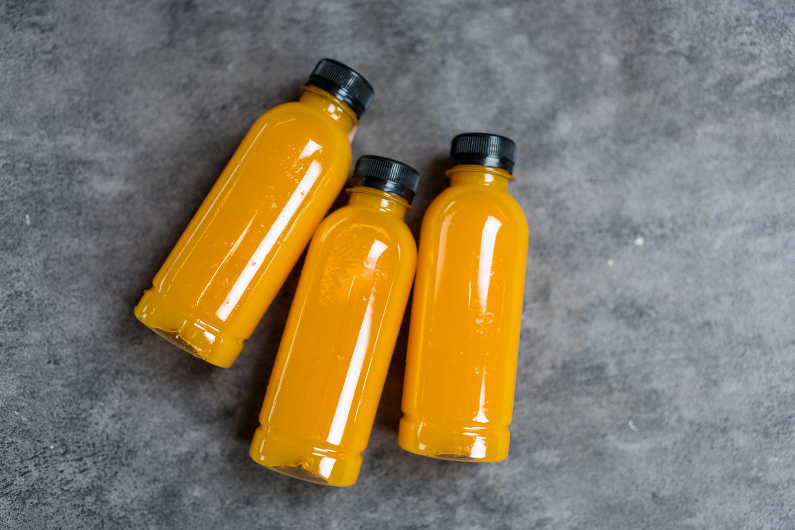 Three of bottles of fresh orange juice, top view