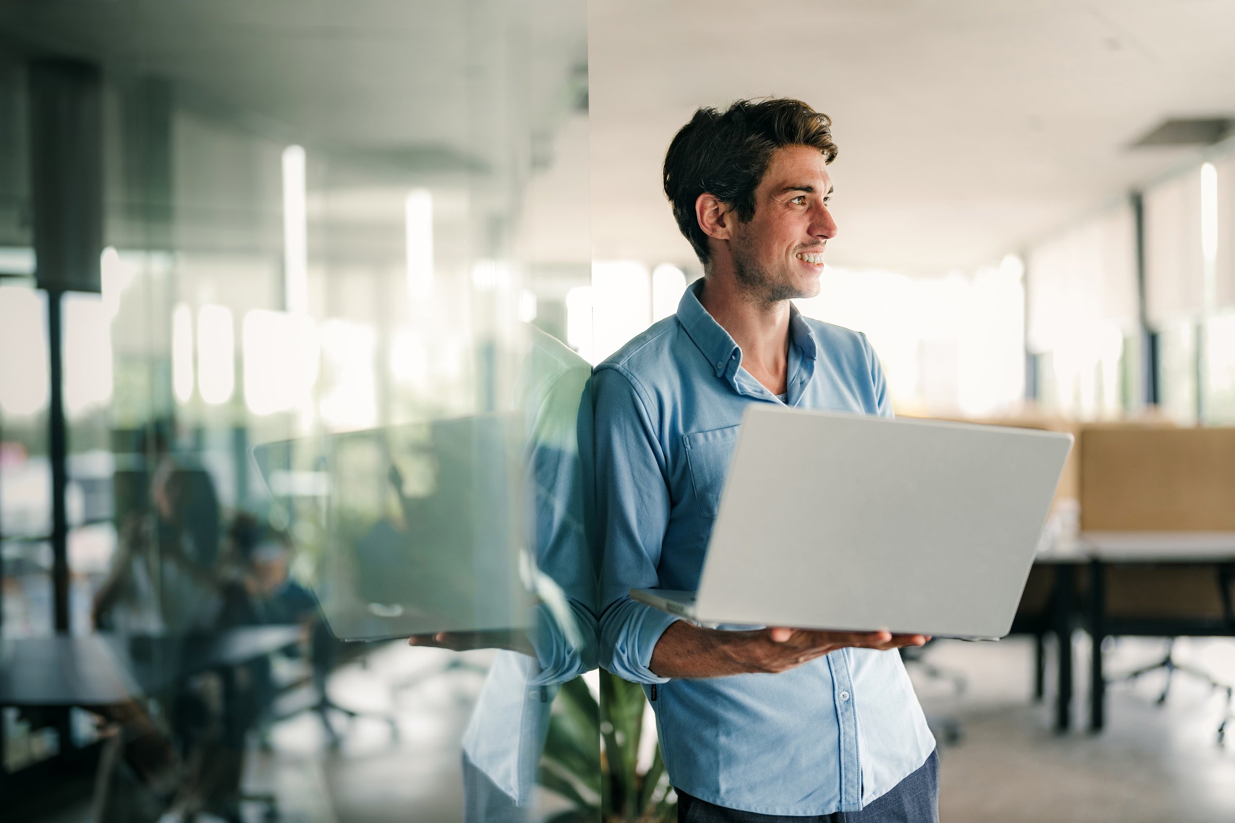 Portrait of a handsome successful young business people, software engineer with laptop in the office. Startup, freelance work, people and technology concept.