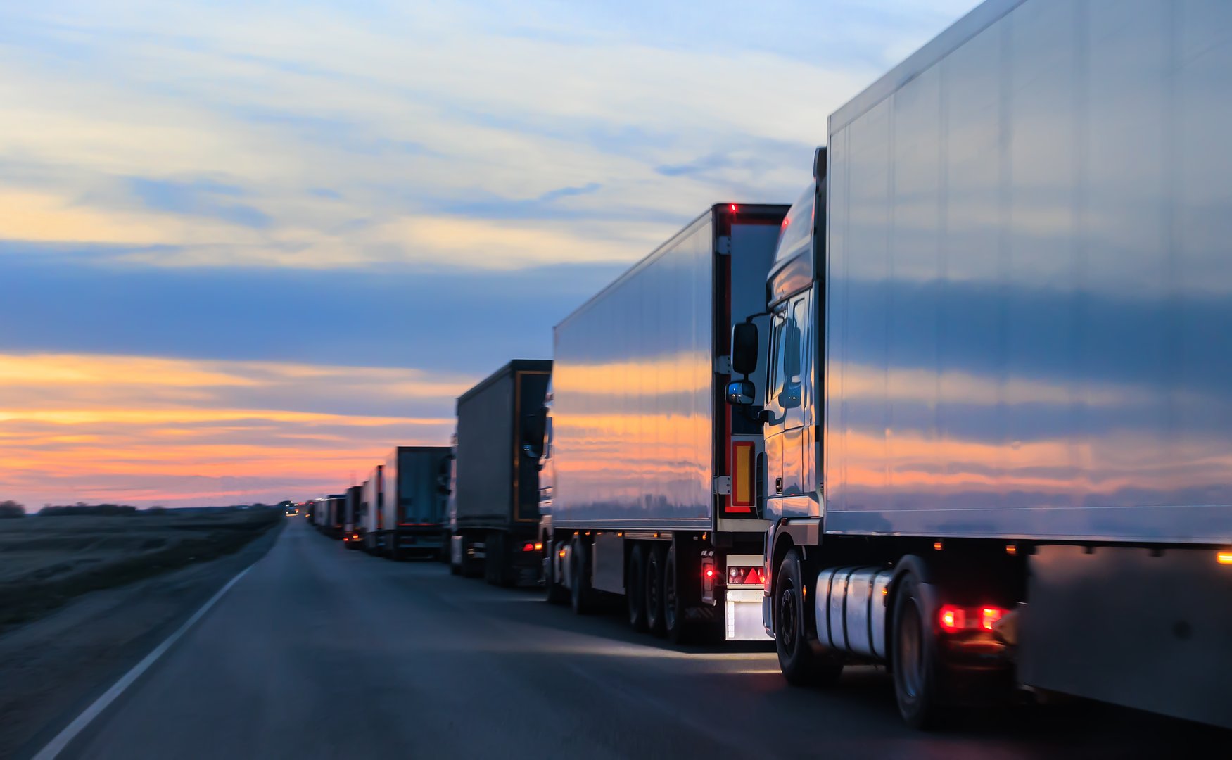 Many Trucks on the Country Road in the Evening at Sunset