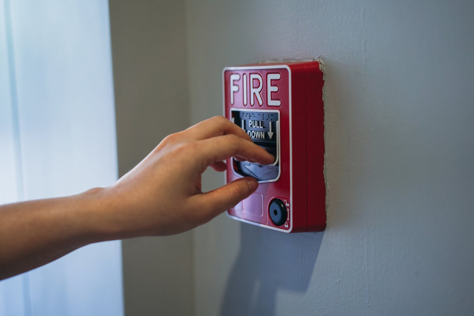Close up hand pull fire alarm on the wall beside the door. Break the glass and press the button to activate.