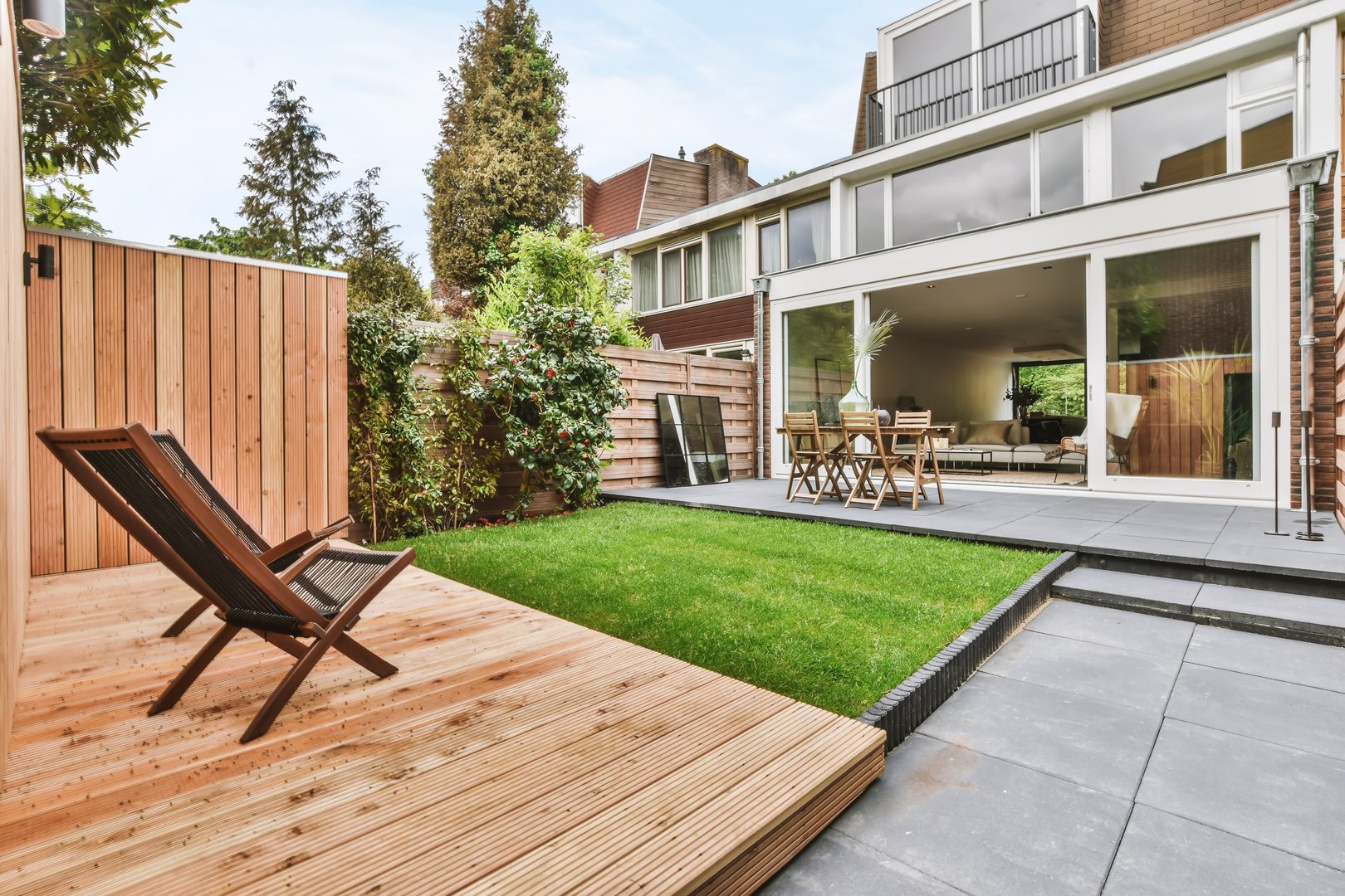 Stylish and well-maintained courtyard of the house with wooden table and chairs and a fresh lawn