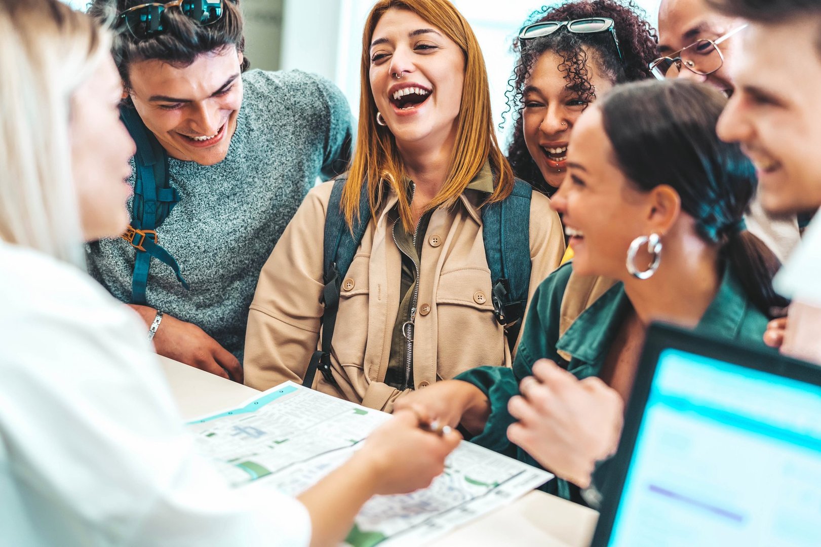 Group of young people doing check-in of youth hostel guest house - Happy tourists talking with receptionist at hotel lobby - Summer vacations and tourism concept