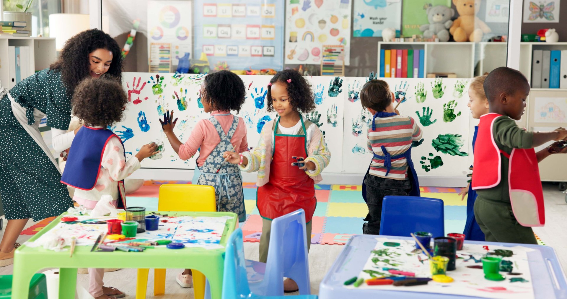 Handprint, painting and children with paper in classroom for creative lesson, education and development. School, students and kids learning with colors for fun activity, art project and motor skills