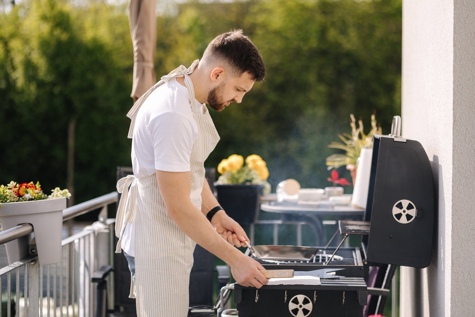 Handsome bearded man hold carbon steel pan and preparing for frying meat on grill. High quality photo