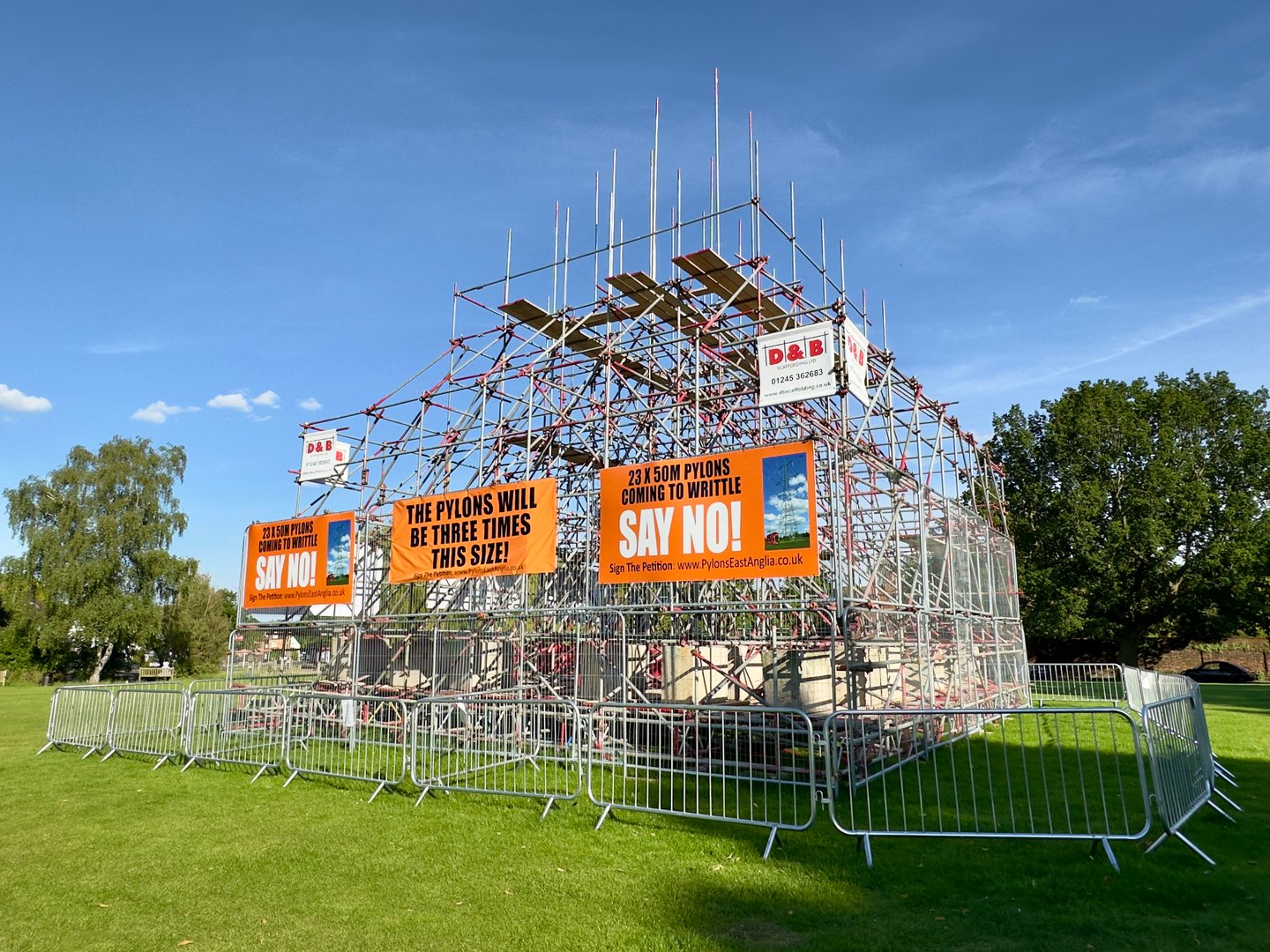 Writtle, UK - June 17, 2024: Scaffolding erected on the village green in protest and to encourage the public to sign a petition against new electricity pylons in East Anglia, Writtle, Essex, UK.