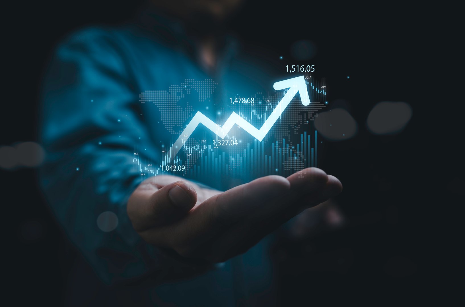 Businessman holding glowing increasing up arrow with stock market graph chart and world map for global economic growth concept.