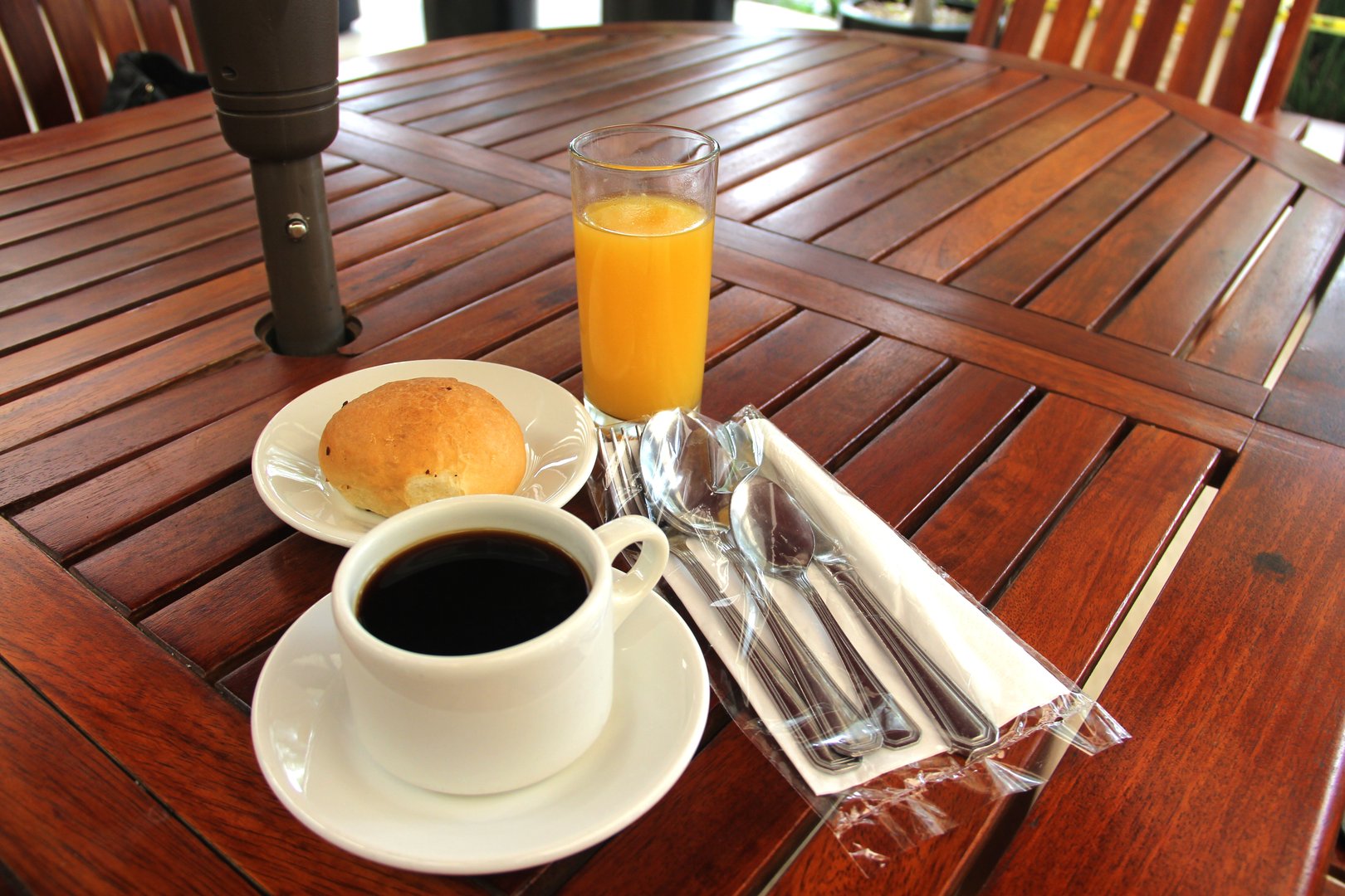the breakfast with coffee, bread and juice with sanitized cutlery on a wooden deck in the garden, a new normal for covid-19 prevention
