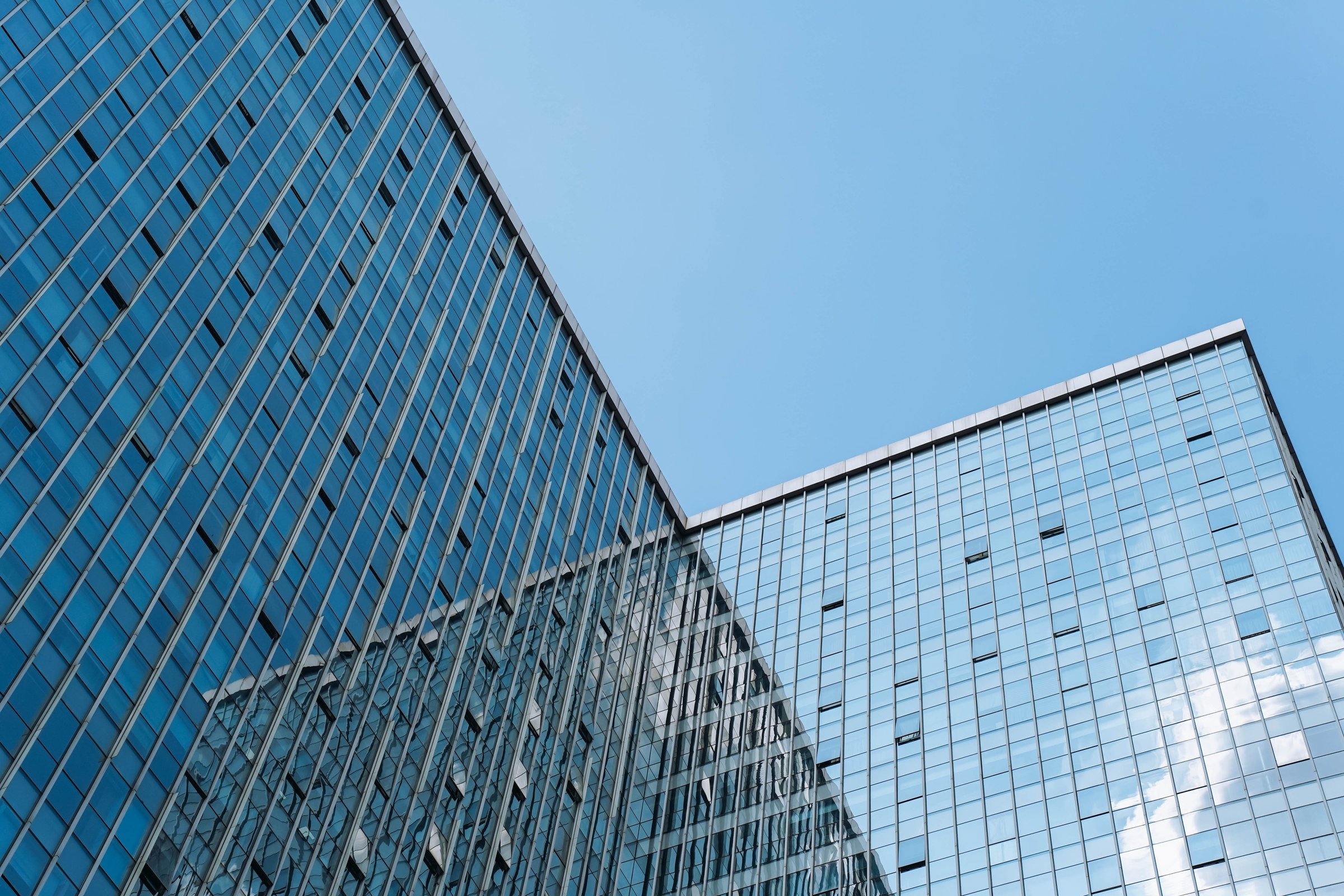 Low angle view of skyscraper with glass window and clear blue sky background for business and finance concept