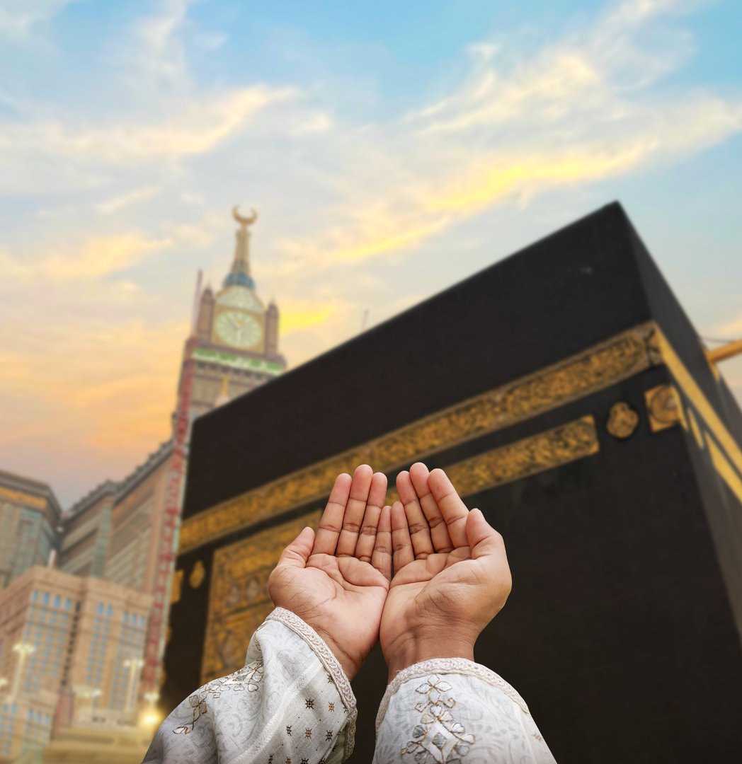 Hand of Muslim man praying with mosque background. Islamic wallpaper concept of eid, Ramadan, prayer and Hajj.
