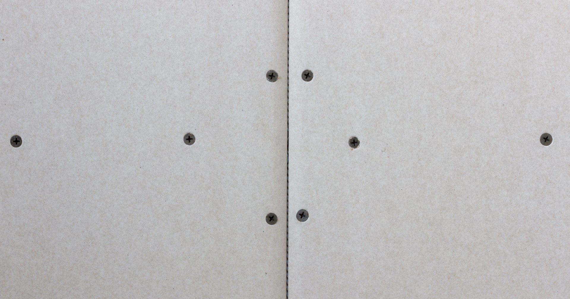 Close up of drywall panels with visible screws, showcasing construction details for interior wall installation.