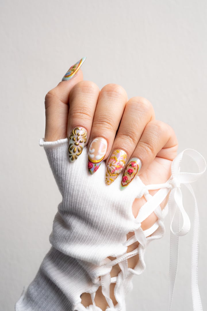 Hands with beautiful khaki manicure and gold foil. A woman is holding a branch with white flowers. Beauty industry.