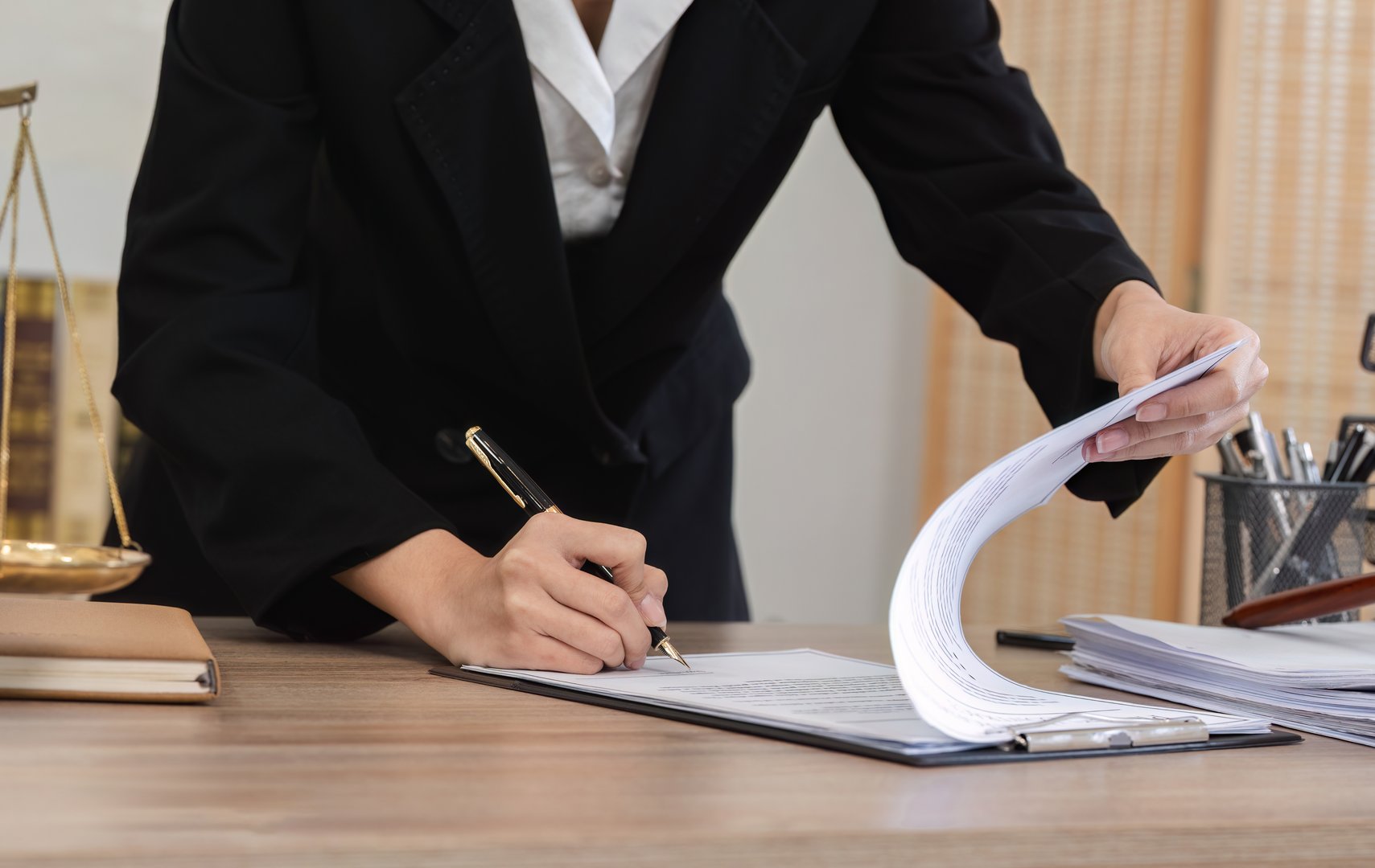 A young lawyer in a modern office setting is introducing and signing contract documents with clients, showcasing professionalism and legal expertise.