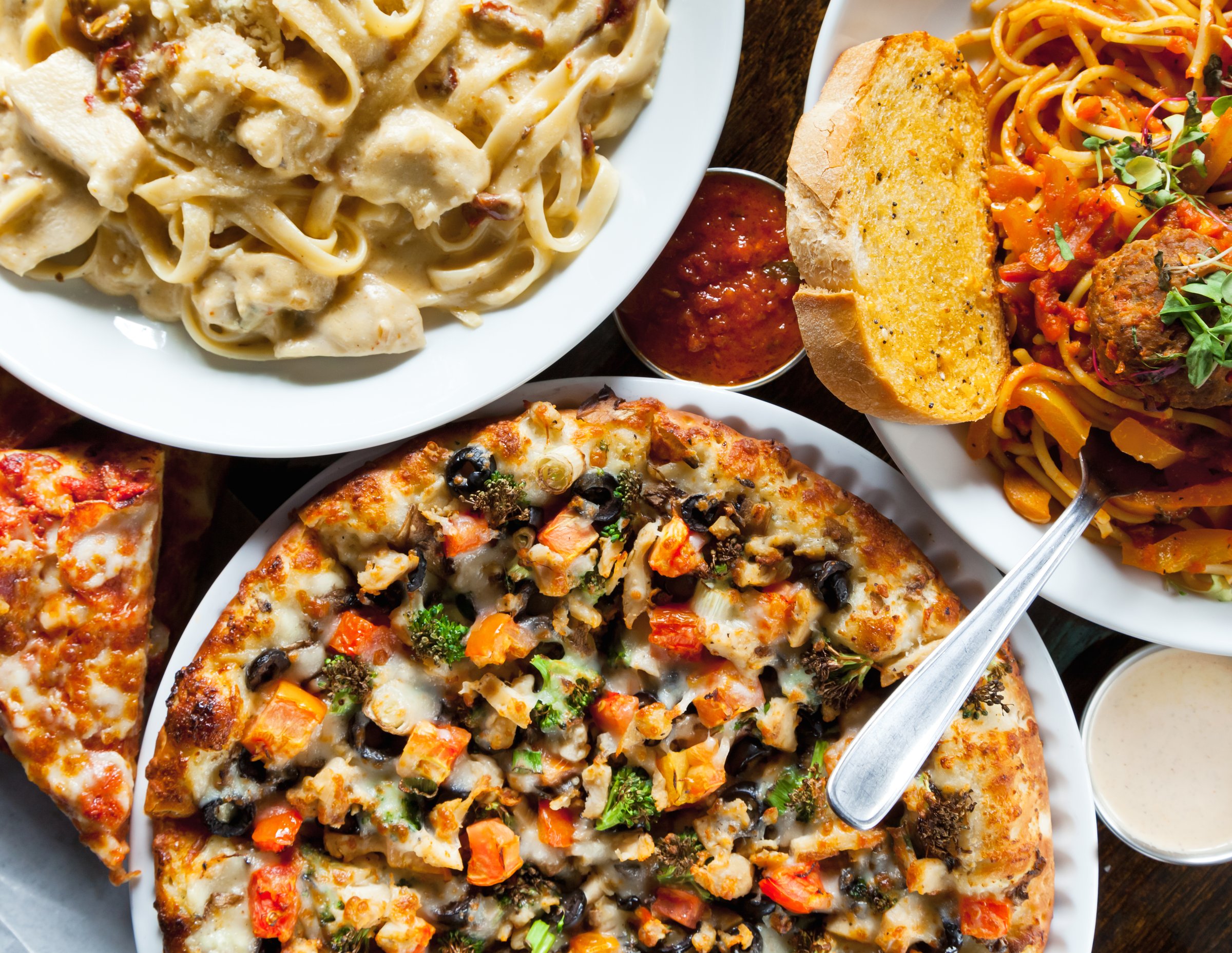 Top-down image of an Italian dinner with pizza, spaghetti, meatballs, and chicken alfredo.