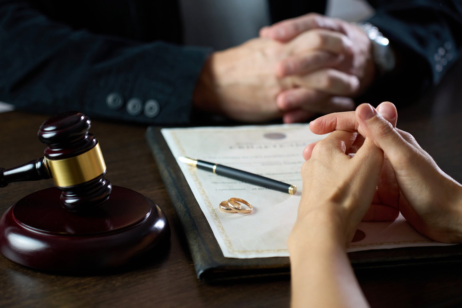 Couple sitting at table with divorce document, close-up, selective focus. Signing divorce agreement