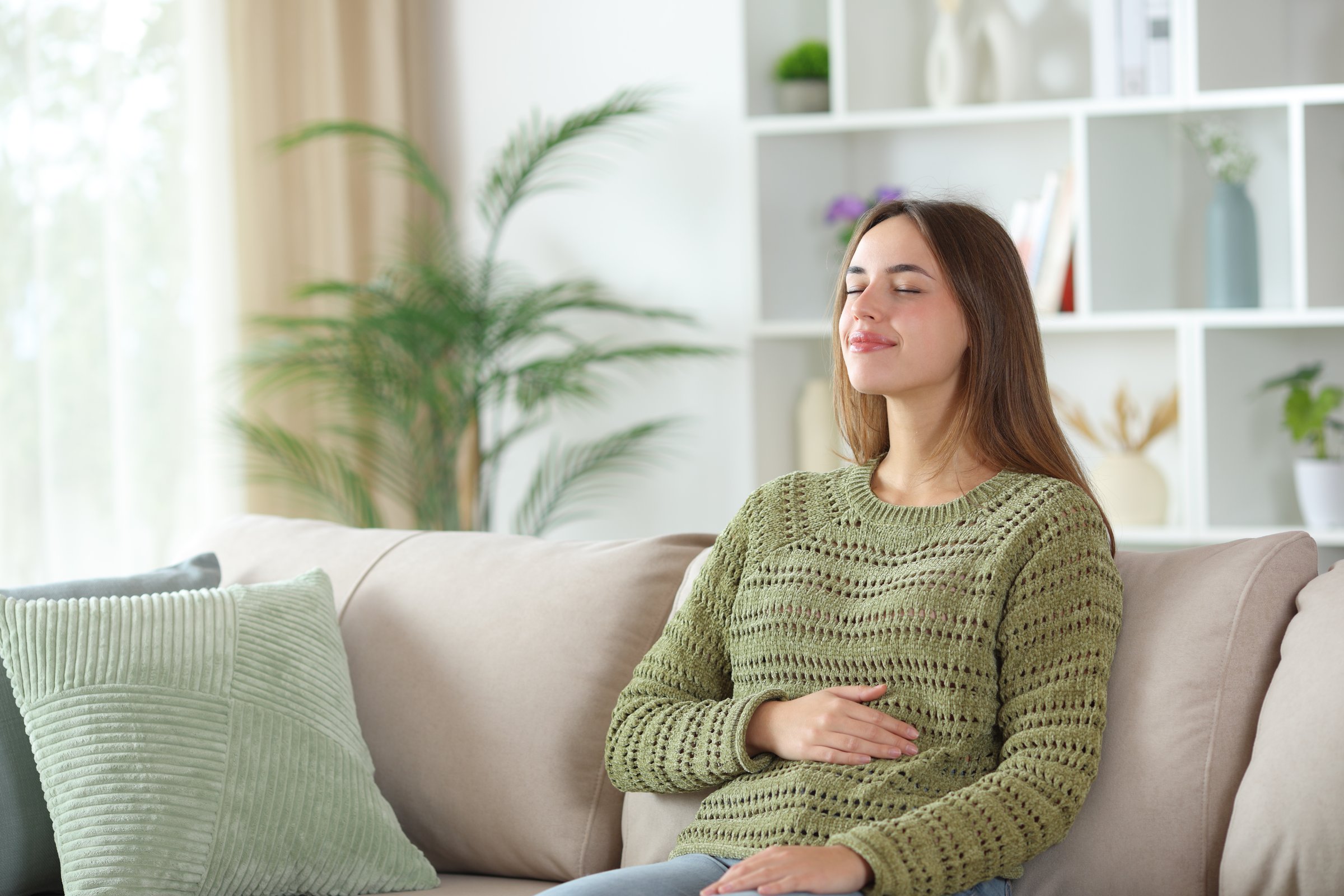 Woman enjoying a healthy bowel tract sitting on a couch at home