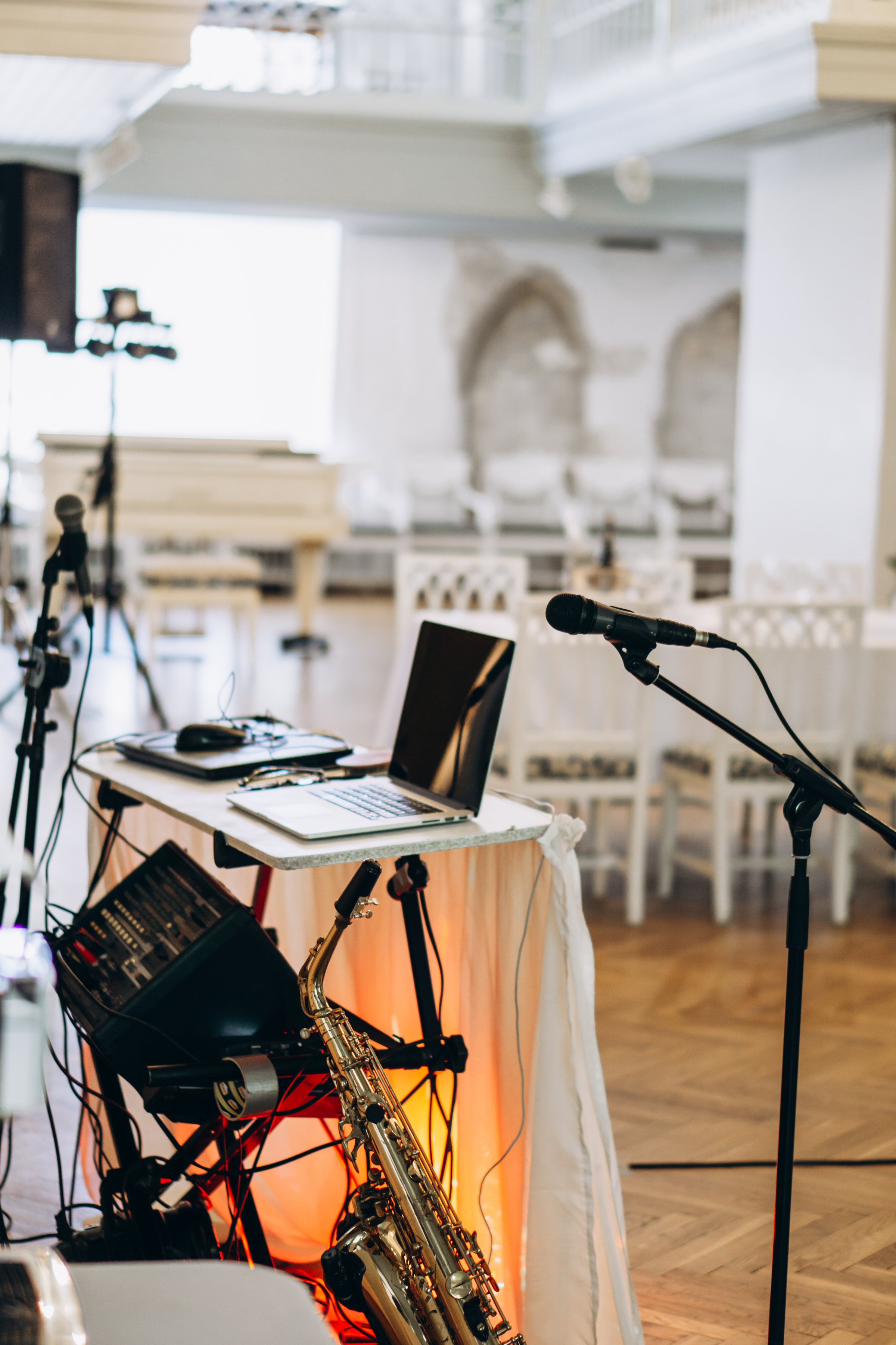 Elegant music setup with laptop, saxophone, and microphones prepared for a live performance in a sophisticated event venue wedding DJ musician . High quality photo