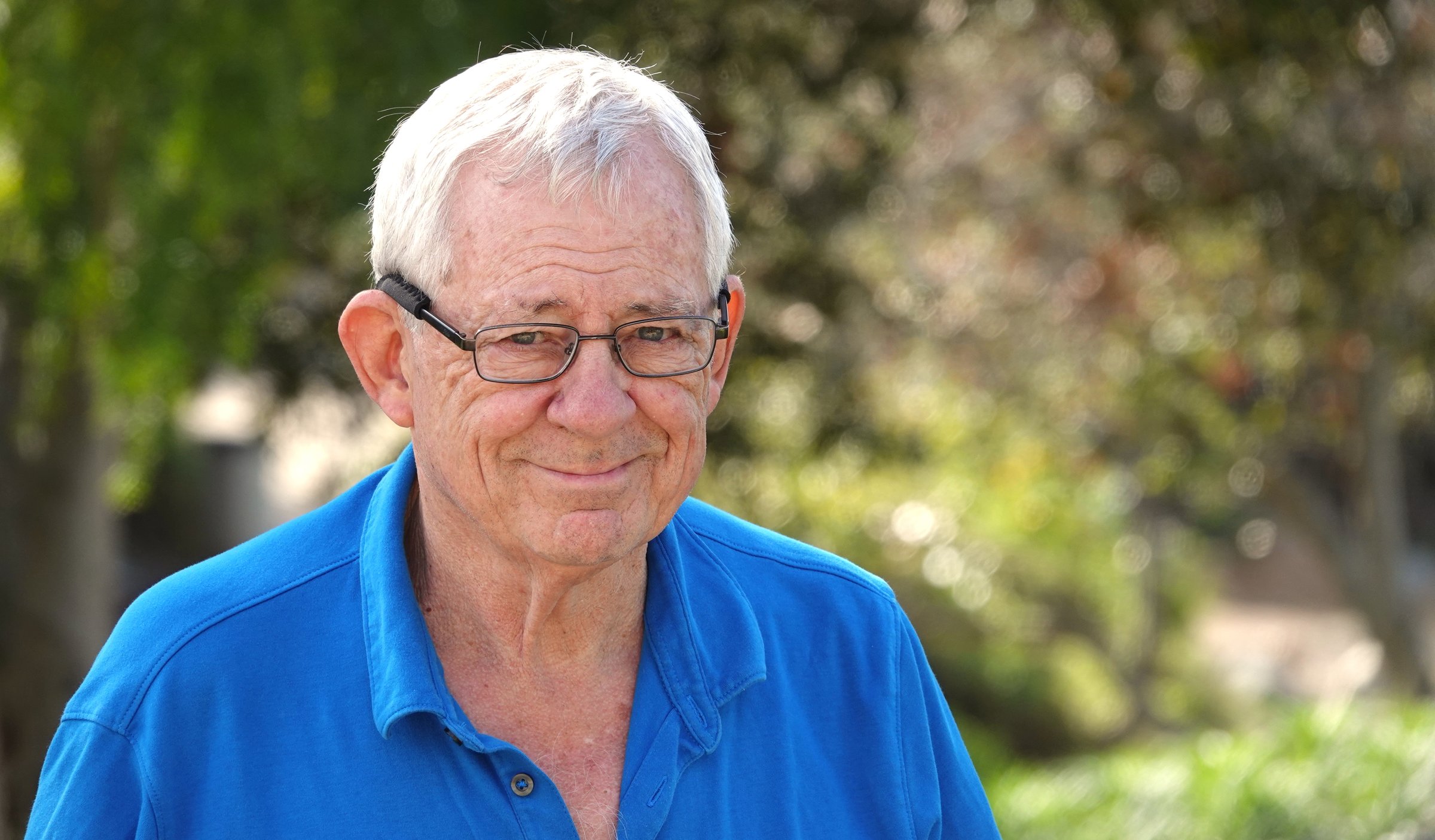 A shallow focus of an elderly smiling Caucasian man wearing eyeglasses with a kind facial expression