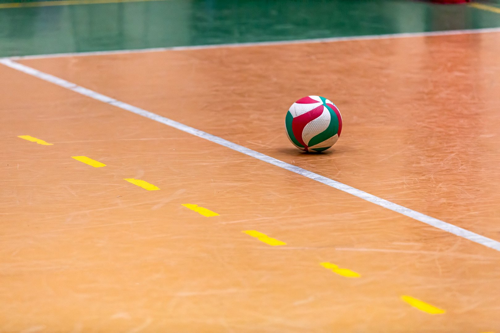 Colorful volleyball on an indoor court with yellow and white game lines. Sporty and dynamic atmosphere.