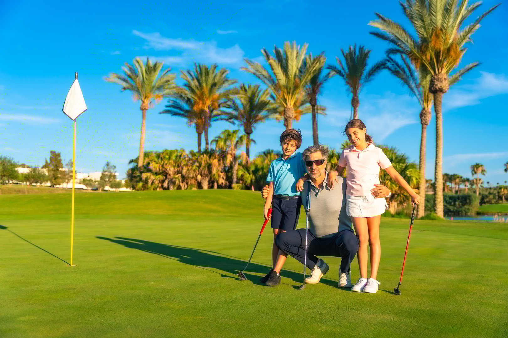Portrait with copy space of a male caucasian adult golf instructor with two students in a green luxury course