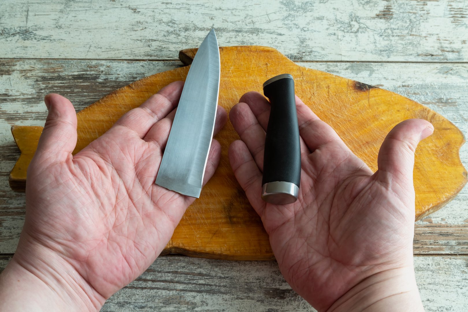 A close-up of a hand holding a broken blade of a kitchen knife demonstrates the consequences of using cheap counterfeits. The metallic fracture is clearly visible, emphasizing the low quality of the material.