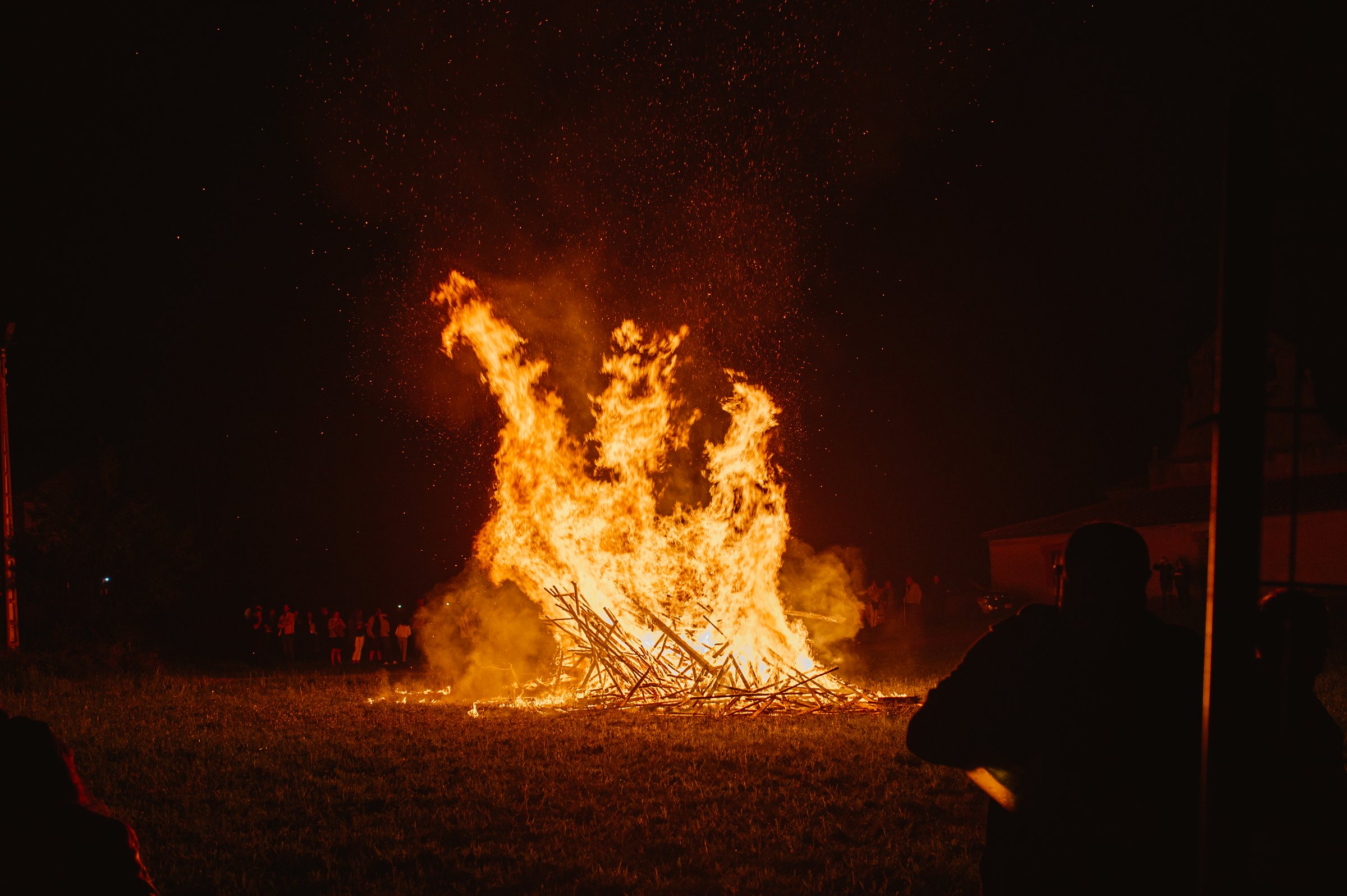 Group of unrecognizable people around a large bonfire during the celebration of Litha, an ancient pagan festival that Christianity turned into the night of St. John.