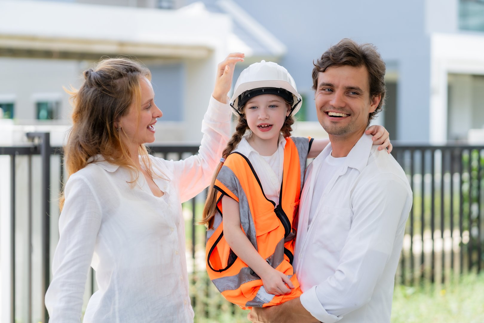 A little female architect in her father's arms and supported by her mother, symbolizing the love and warmth of family, the idea of supporting children's dreams from a young age.