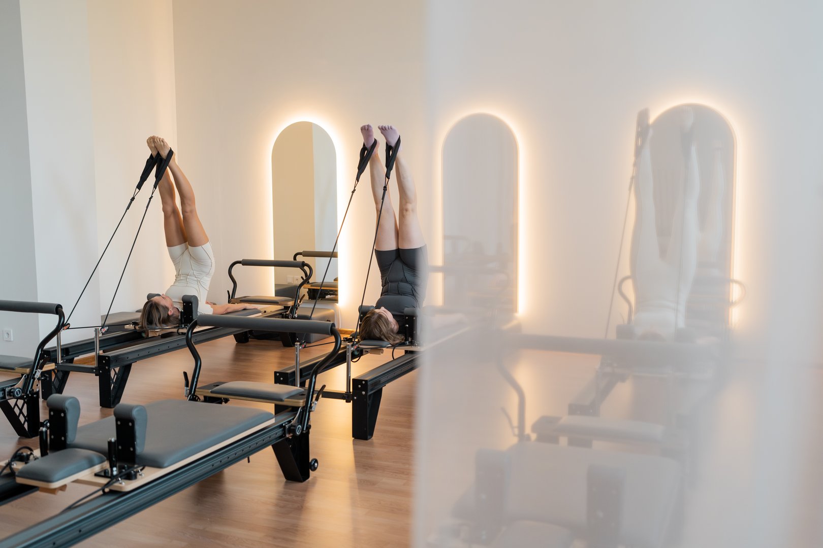 Calm reformer room with mirrors, Peaceful Pilates space with warm lighting and wooden floors