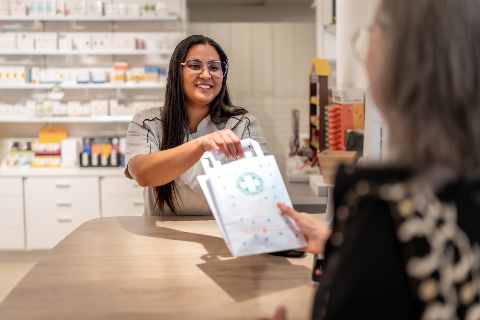 Pharmacist giving medicine into paper bag to a customer at the counter