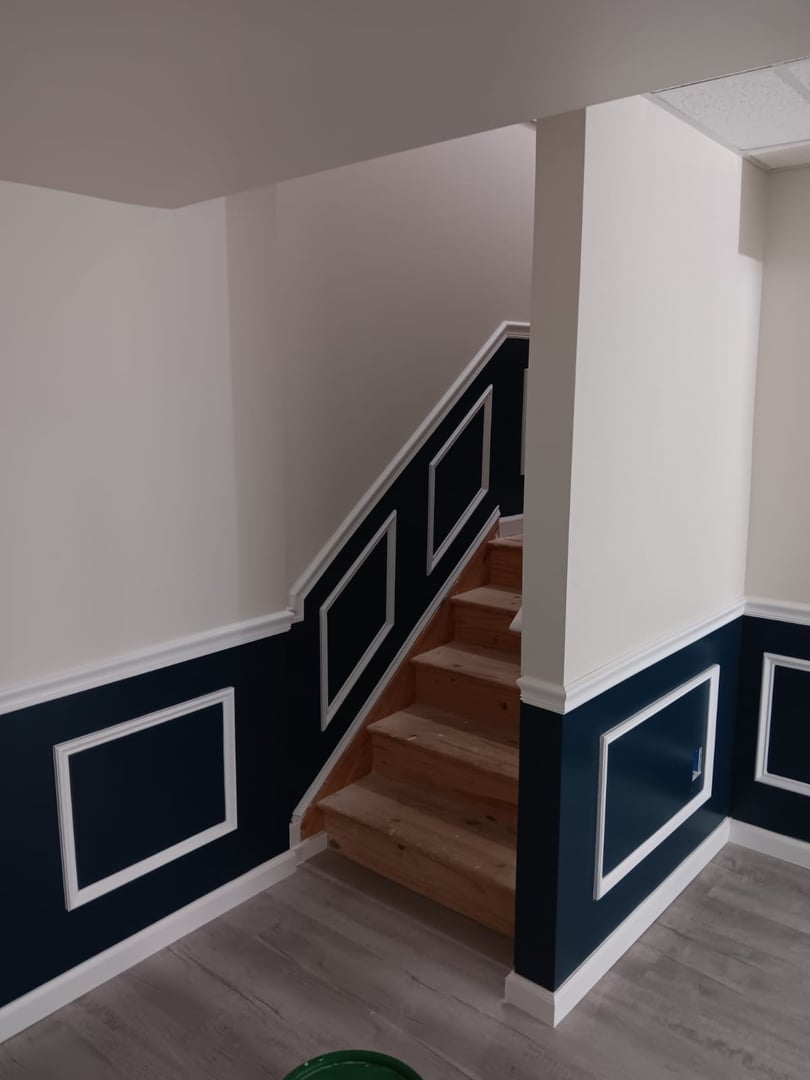 Staircase with wooden steps and blue wall paneling with white trim in a modern interior space.