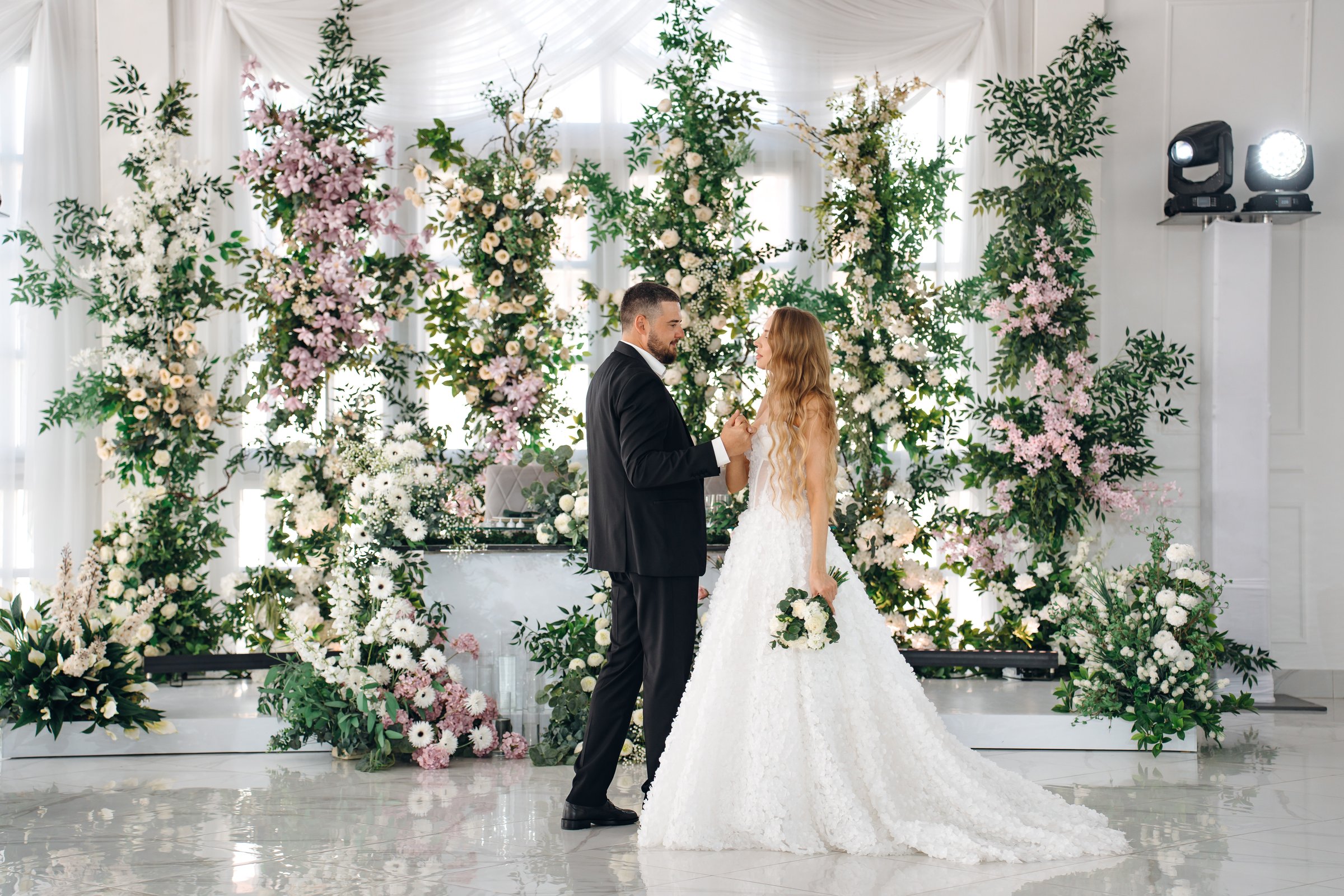 Beautiful and in love newlyweds dance in a banquet hall decorated with flower arrangements. wedding traditions.