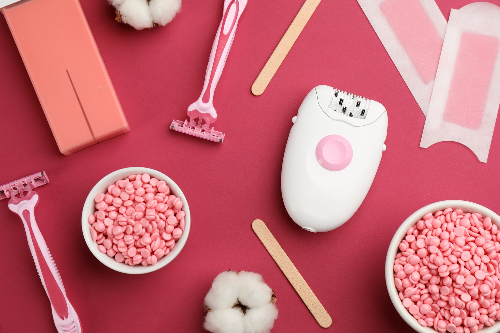 Set of epilation products on crimson background, flat lay