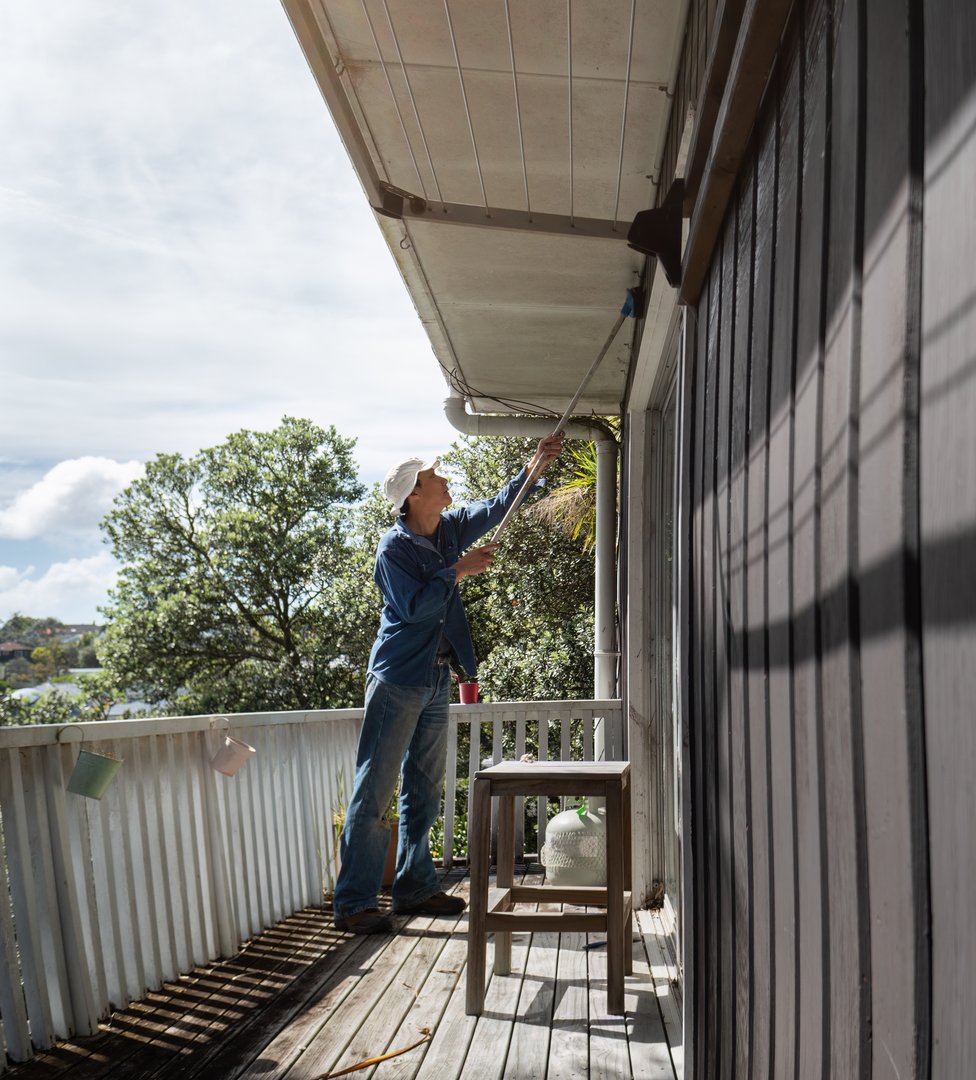 Außenwand- und Fassadenreinigung - Mann reinigt Hauswand mit Bürste für Hausreinigung