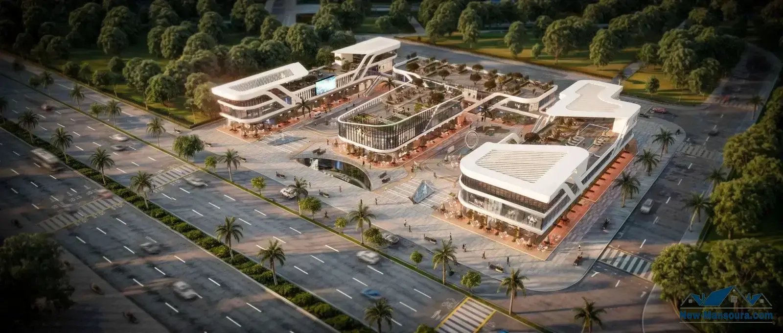 Aerial view of a modern commercial complex with curvy roofs, surrounded by roads and palm trees, nestled in a green area.