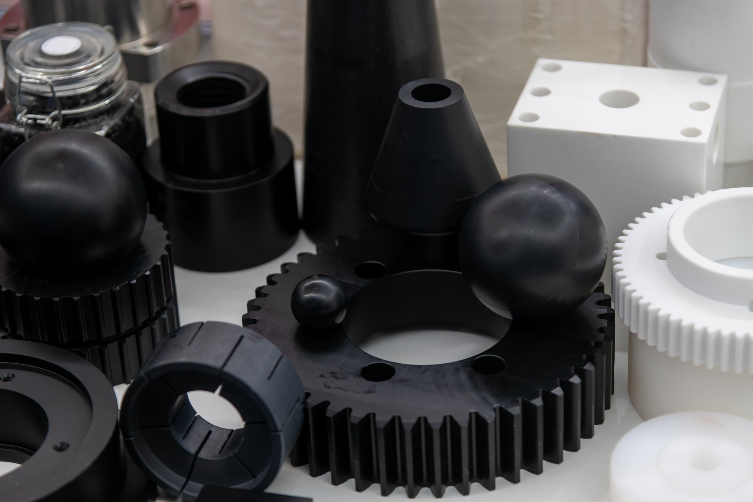 An array of black and white plastic spare parts arranged attractively in a modern display case highlights advancements in manufacturing techniques and material design.