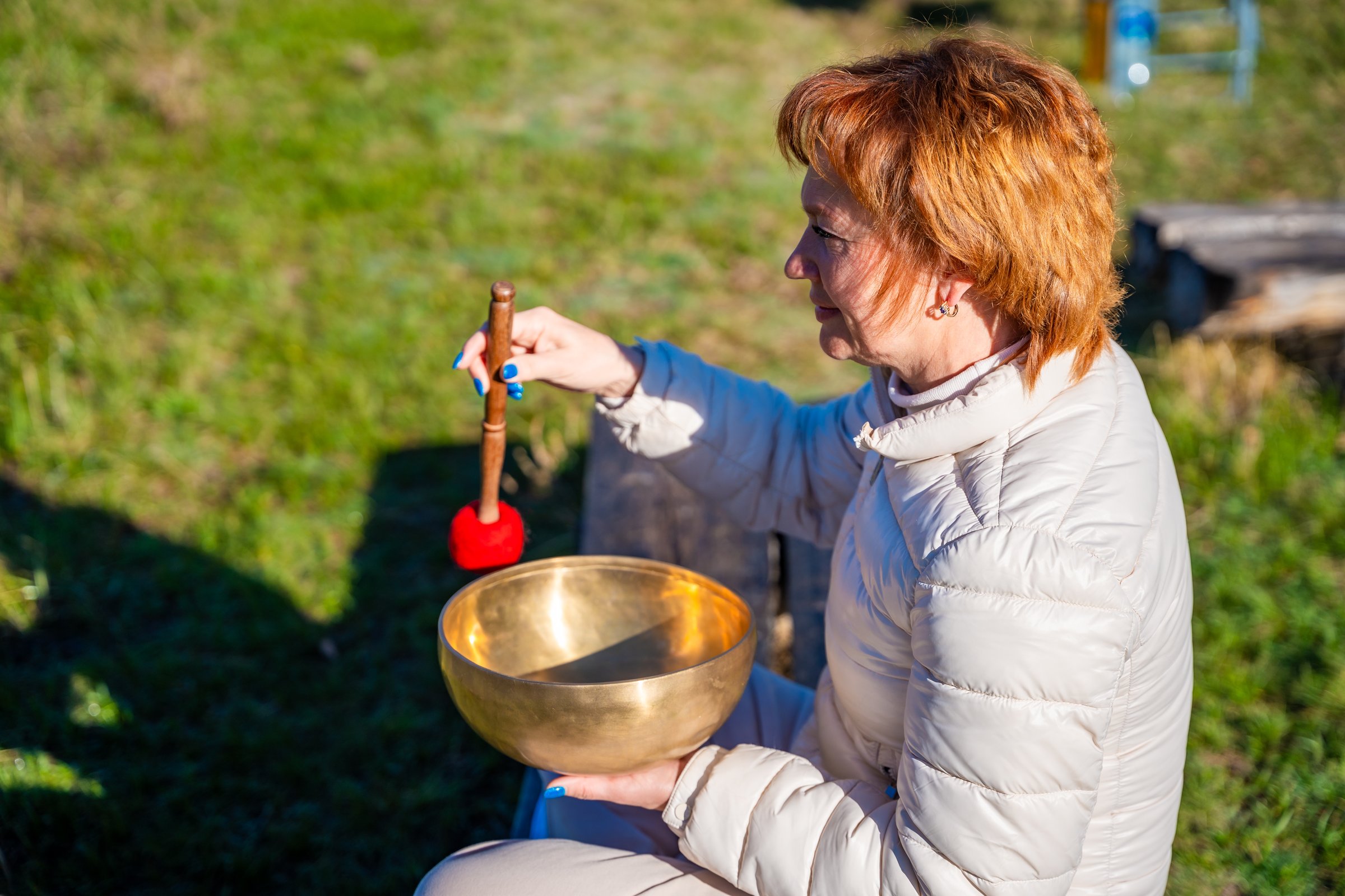 Woman playing a Tibetan singing bowl by a mountain river in Altai. Concept of sound healing, spiritual alignment, and deep connection with natural elements. High quality photo