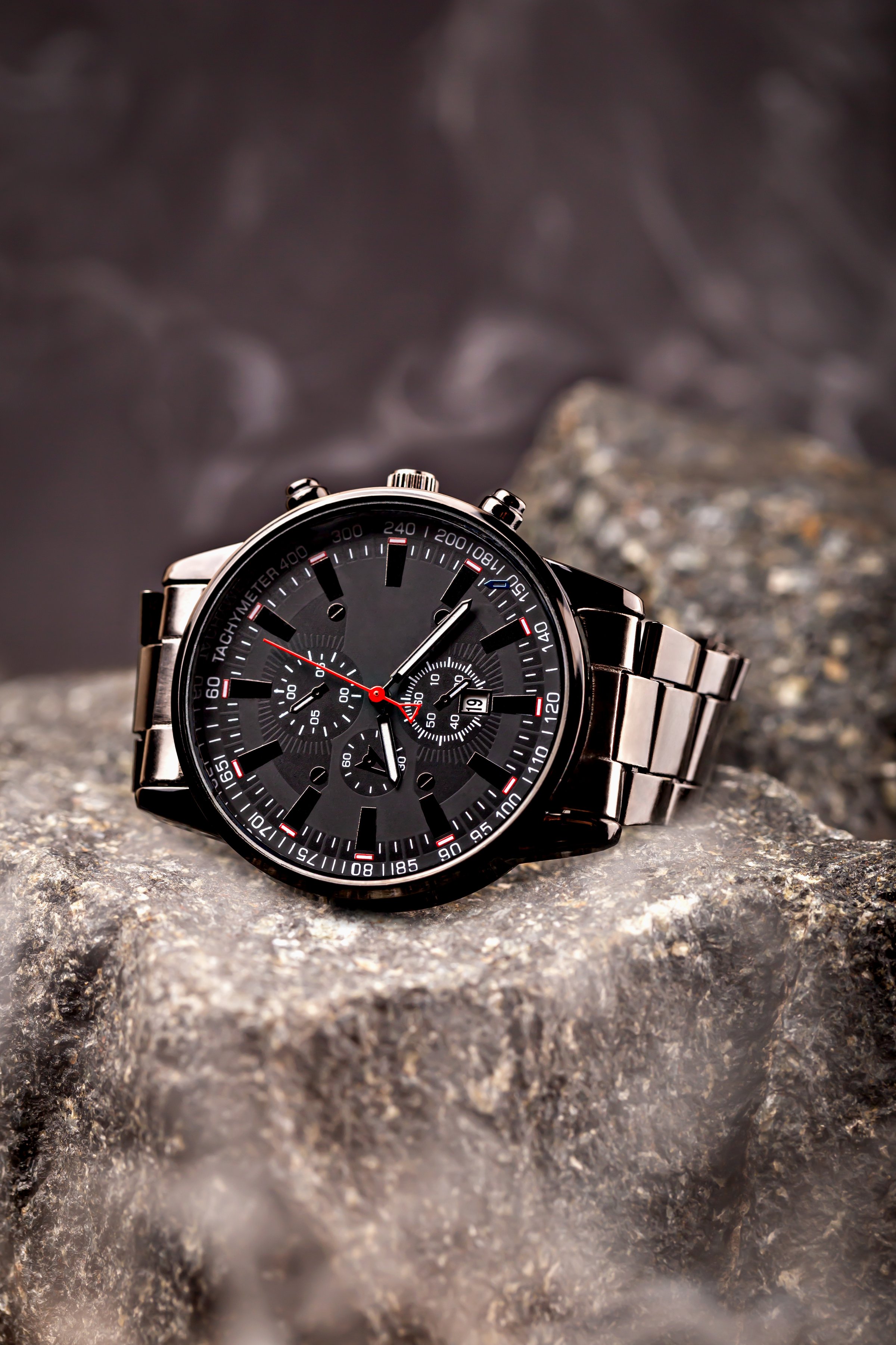 Stainless steel watch with black dial placed on textured stone surface. Premium timepiece symbolizing strength, durability, and sophistication. Concept of masculine style and resilience