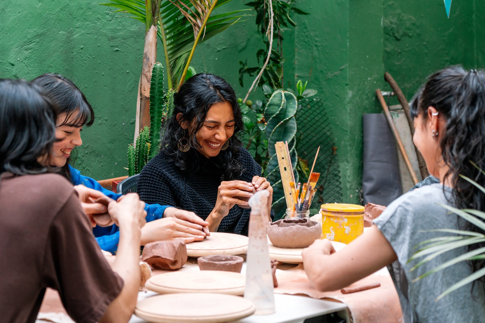 Group of Latin women engaged in creating handmade ceramic pieces during an inspiring pottery workshop, fostering creativity and community