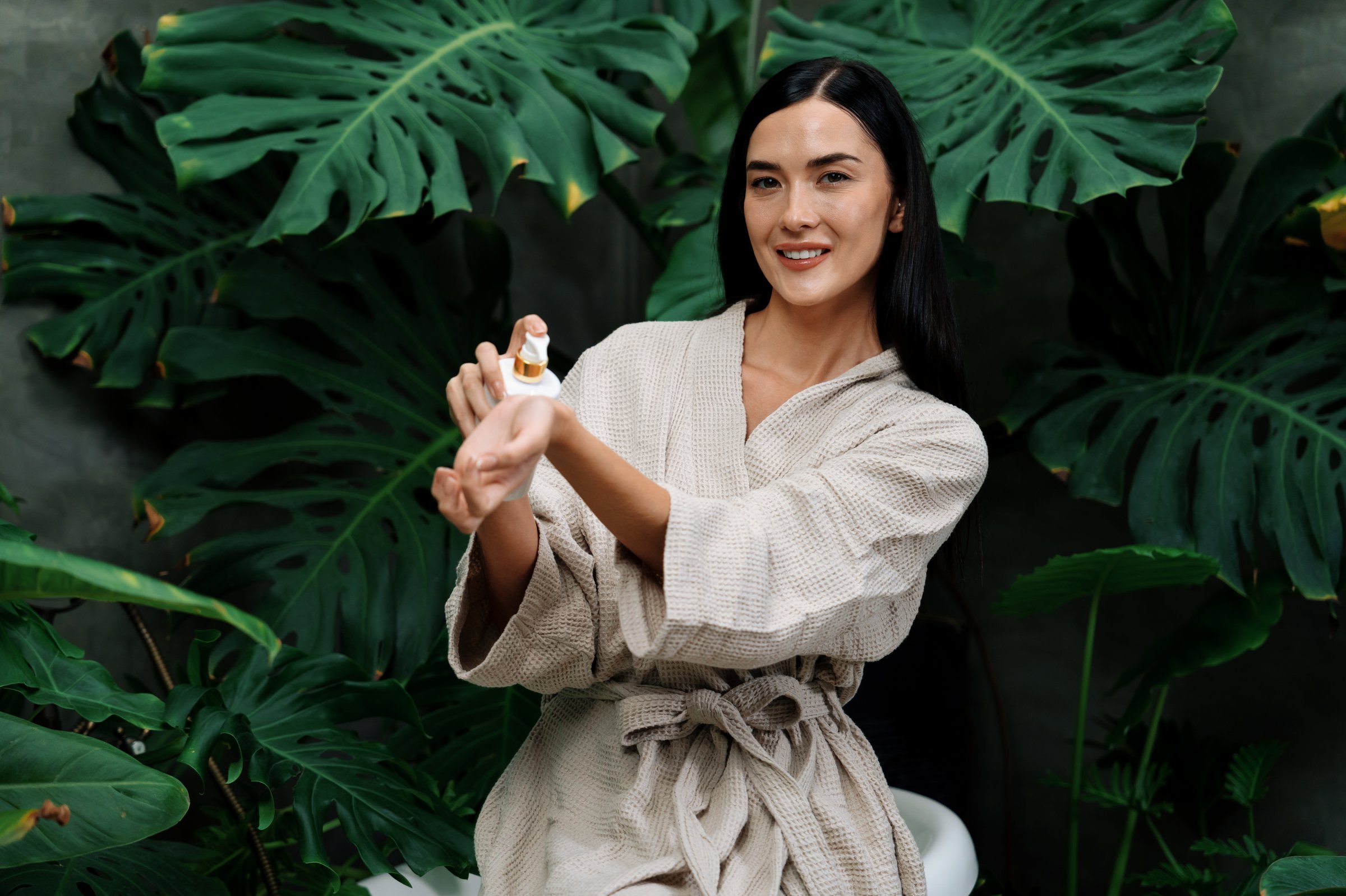 Tropical and exotic spa garden with bathtub in modern hotel or resort with woman in bathrobe holding beauty skincare product