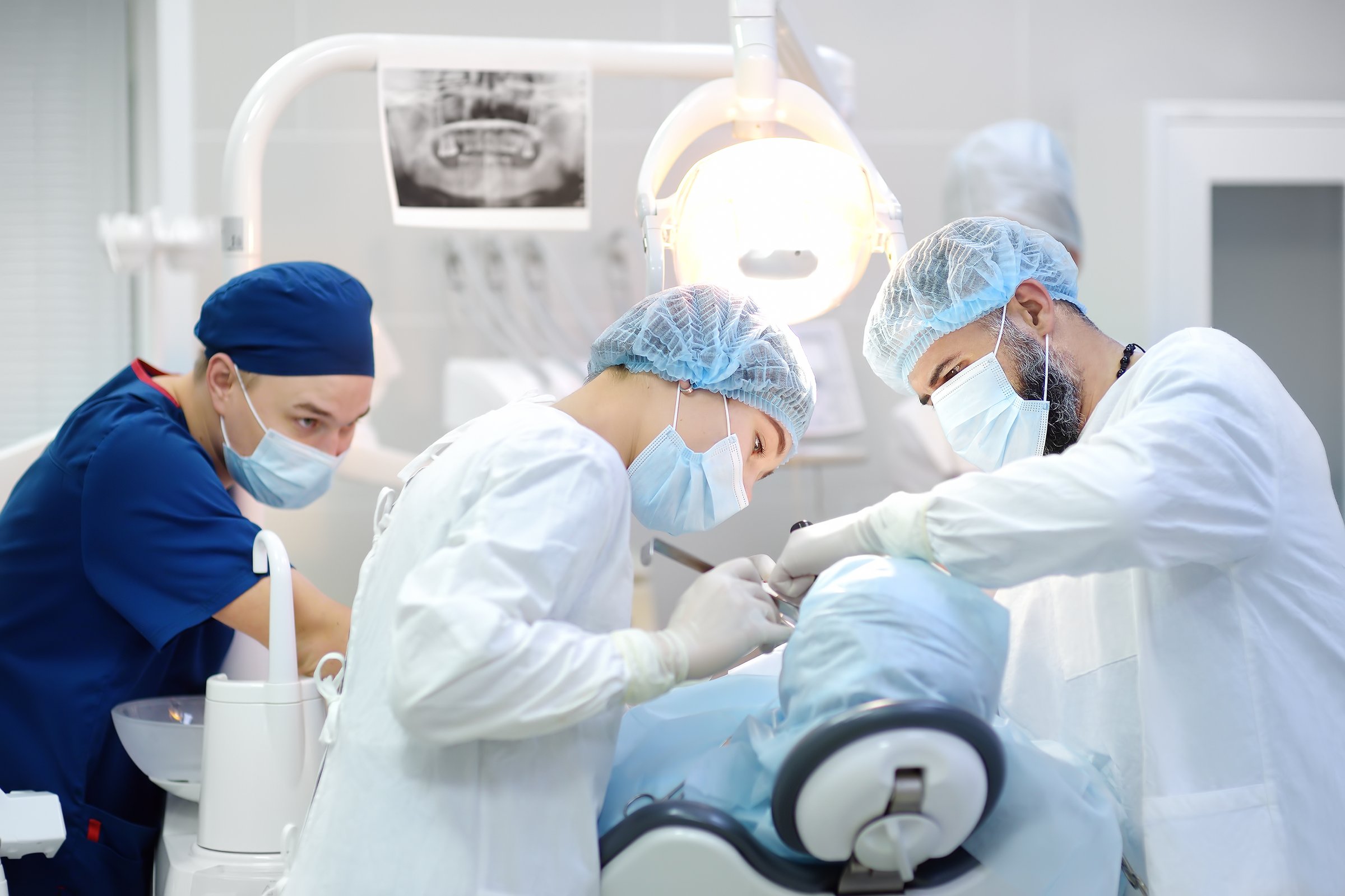 Surgeon and nurse during a dental operation.Anesthetized patient in the operating room.Installation of dental implants or tooth extraction in the clinic. General anesthesia during orthodontic surgery.