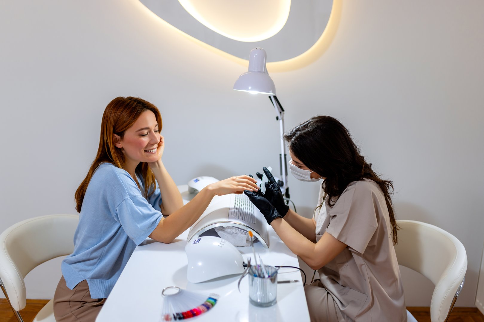 Manicurist filing client's nails at the beauty salon.