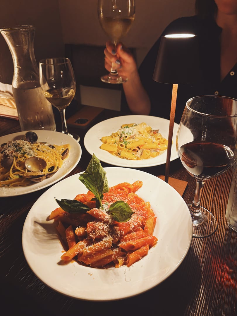 Three plates of pasta and wine in a dark cozy historic Italian restaurant