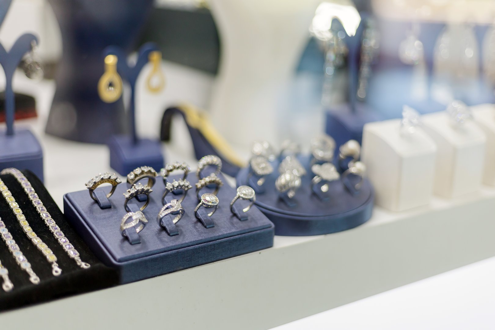 A diverse array of beautiful rings, earrings, and bracelets is displayed in an elegant jewelry store. The shiny pieces catch the light, inviting customers to admire the craftsmanship.